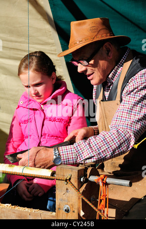 Mann auf einer Drehbank Pedal demonstrieren Pole Drehmaschine drehen, Stuhl Spindeln auf der Herbst-Landschaft-Show machen Stockfoto