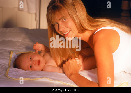 Mutter Betrieb 6 Monate altes Baby im Bett bei Sonnenaufgang Licht Stockfoto