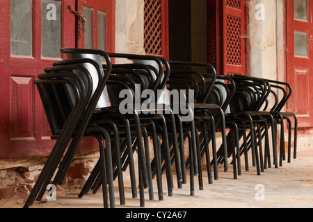 Viele schwarze Metall-Stühle gestapelt auf einem alten Gebäude Stockfoto