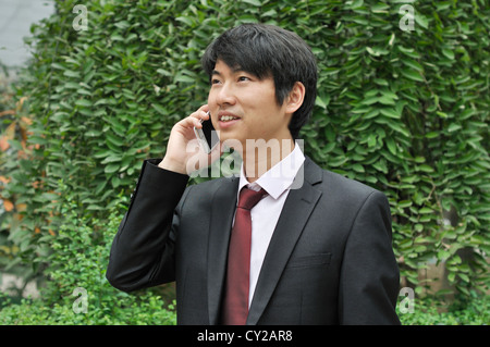 asiatische Geschäftsmann nutzt Handy in der Natur. Stockfoto