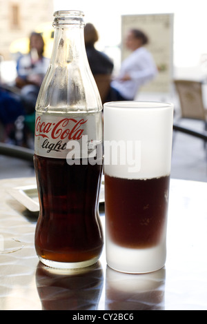 Gefüllte Flasche Soda mit einem halben Glas auf einem Tisch Stockfoto