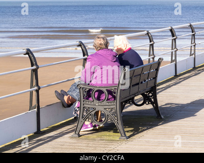 Zwei ältere Dame Freunden plaudern in der Sonne sitzen auf Saltburn pier Stockfoto