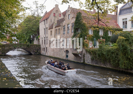 Touristen genießen eine Bootsfahrt auf einem wunderschönen Kanal in der belgischen Stadt Brügge Stockfoto