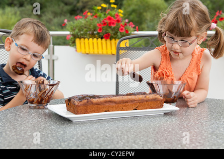 Kinder schmücken den Schokoladenkuchen Stockfoto