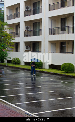 Ein Mann geht über den Hotel-Parkplatz bei starkem Regen HAi Phong Vietnam Stockfoto
