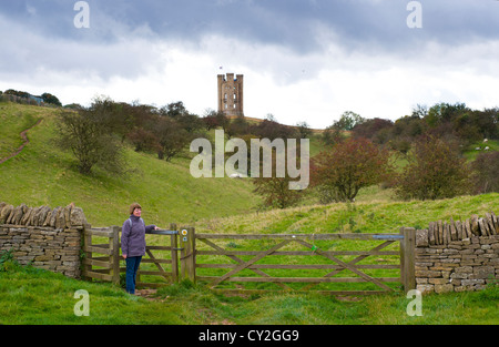 Frau Walker, an küssen Tor auf den Cotswold-Weg-Wanderweg mit Broadway Tower Torheit auf Broadway Hügel in Ferne, Stockfoto