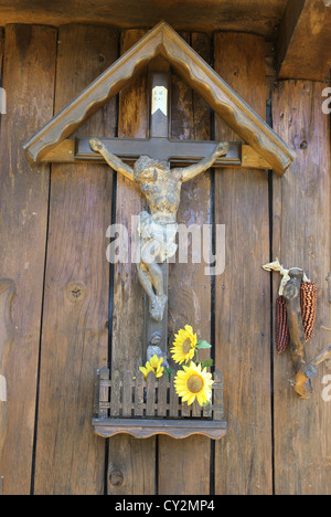 Hölzerne Jesus am Kreuz mit Statuette und Sonnenblumen Stockfoto