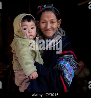 Schwarze Hmong Großmutter mit ihrem Enkel In die Arme, Sapa, Vietnam Stockfoto