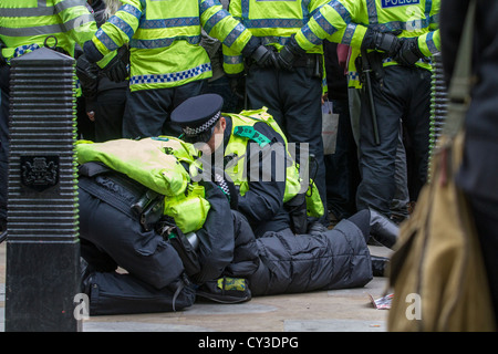 Polizisten kümmern sich um einen verletzten Demonstranten bei der Stop The War-Rallye am Trafalgar Square in London am 8. Oktober 2011 Stockfoto