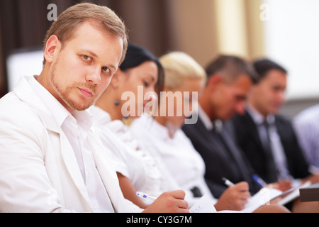 Business-Leute sitzen in einer Reihe zu treffen und sich Notizen macht Stockfoto