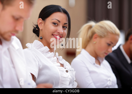 Lächelnde Frau sitzt an einem Business-Meeting mit Kollegen im Büro Stockfoto