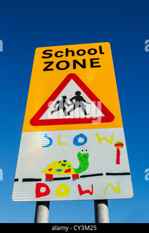 "Slow Down" auf Schild in der Nähe von Schule in England, UK Stockfoto