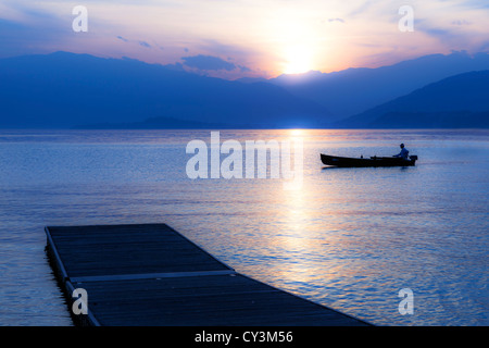 ein Mann in einem Boot auf dem Lago Maggiore in Italien während des Sonnenuntergangs Stockfoto