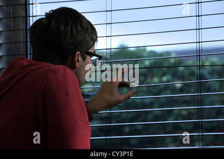 Junger Mann mit Brille, Blick aus einem Fenster sitzen. Stockfoto