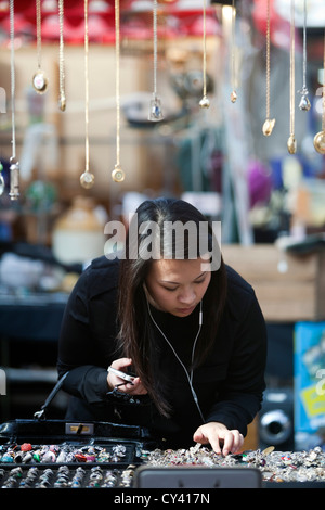 Eine Frau sucht einen Stall in Spitalfields Market, London, UK Stockfoto