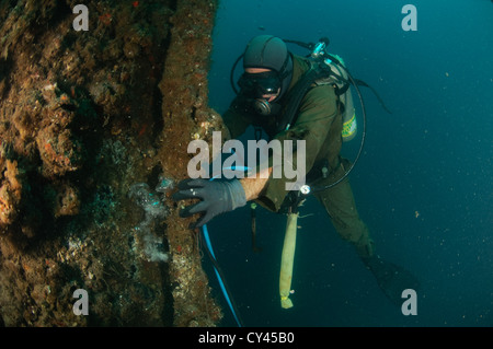 Gewerblicher Taucher unter Wasser Rohre Schweißen. Kabel von der Oberfläche liefern Strom für die Beleuchtung und die Fackel Stockfoto