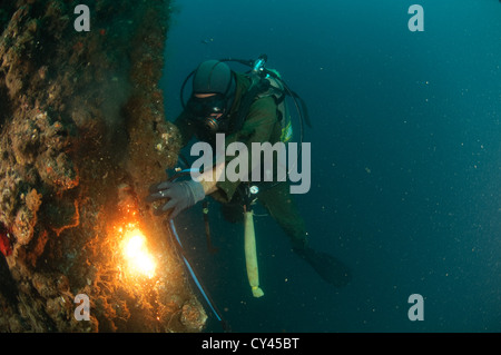 Gewerblicher Taucher unter Wasser Rohre Schweißen. Kabel von der Oberfläche liefern Strom für die Beleuchtung und die Fackel Stockfoto