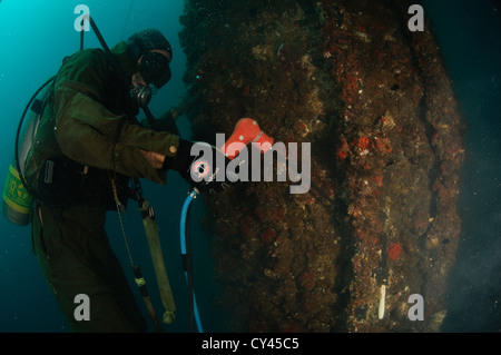 Gewerblicher Taucher unter Wasser Rohre Schweißen. Kabel von der Oberfläche liefern Strom für die Beleuchtung und die Fackel Stockfoto