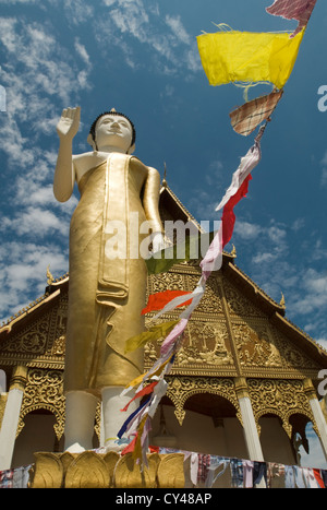 Eine große Statue von Buddha steht vor einem Tempel in der Pha, die Luang Stupa Komplex in Viantiene, Laos Stockfoto