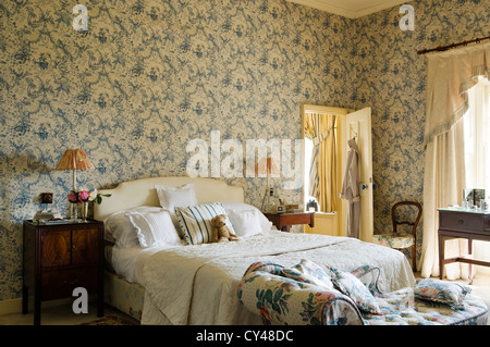 Toile De Jouy Tapete im Schlafzimmer mit floral gemusterten Chaise Lounge am Fuße des Bettes Stockfoto