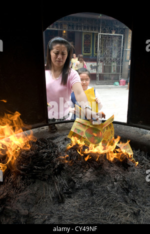 Ein Anhänger brennt Papier 'Glück-Token' in einem Ofen außerhalb der chinesischen Goddess of Mercy Tempel in Georgetown, Penang, Malaysia Stockfoto