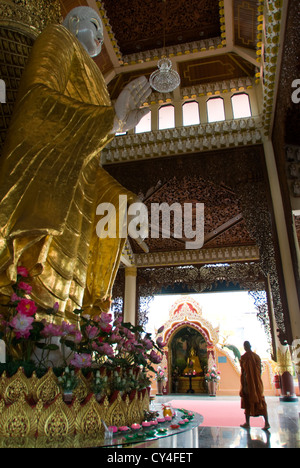 Ein Mönch führt durch eine Halle mit einer großen Statue des Buddha. Dhammikarama Burmesen buddhistische Tempel, Penang, Malaysia. Stockfoto