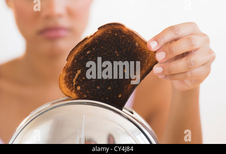 Frau, die von verbranntem Toast aus dem toaster Stockfoto