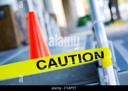 Gelbe Absperrband auf Treppenlift Schiene mit orange Verkehr Kegel hinter sehr geringe Schärfentiefe. Stockfoto