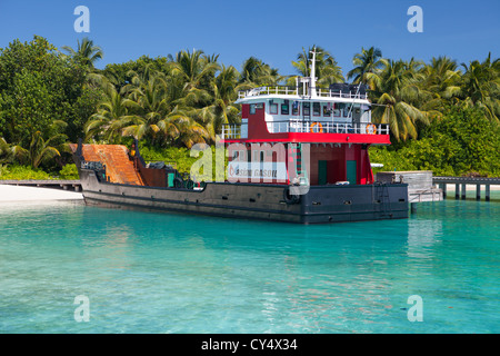 Eine kommerzielle Landungsboote liefern Anlagen Maschinen und Fahrzeuge auf einer einsamen Malediven-Insel Stockfoto