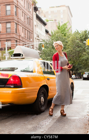 USA, New York State, New York, Frau stehend nahe bei gelbes Taxi auf der Straße Stockfoto