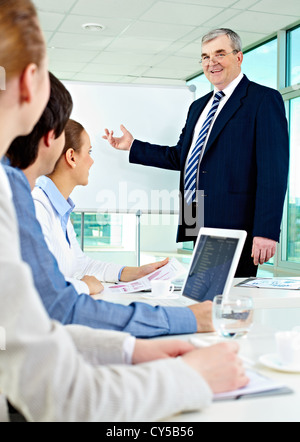 Senior Business-Mann zeigen etwas auf einem Whiteboard an seine Kollegen Stockfoto