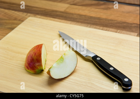 Teilweise geschnittenen Apfel, auf einem Küchenbrett mit einem Messer. Stockfoto