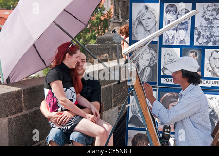 Skizze-Künstler auf der Karlsbrücke Porträt eines jungen Paares tun. Stockfoto