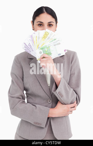 Junge Geschäftsfrau versteckt ihr Gesicht hinter Banknoten Stockfoto