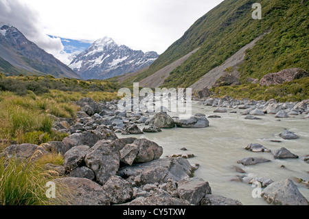 Eiskalte Wasser fließt entlang der Hooker Valley stromabwärts des Hooker-Gletschers, mit der majestätischen Gipfel des Mt. Cook in der Ferne Stockfoto