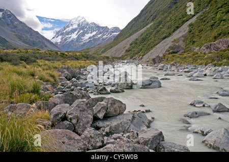 Eiskalte Wasser fließt entlang der Hooker Valley stromabwärts des Hooker-Gletschers, mit der majestätischen Gipfel des Mt. Cook in der Ferne Stockfoto