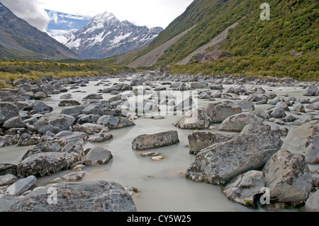 Eiskalte Wasser fließt entlang der Hooker Valley stromabwärts des Hooker-Gletschers, mit der majestätischen Gipfel des Mt. Cook in der Ferne Stockfoto