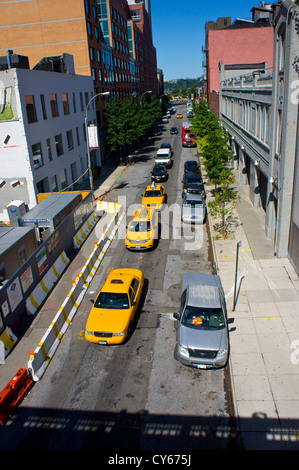 Drei gelben Taxis und anderen Autos bilden eine Linie in einer Straße an der niedrigeren Westseite von Manhattan, New York. Gesehen aus der High LIne. Stockfoto