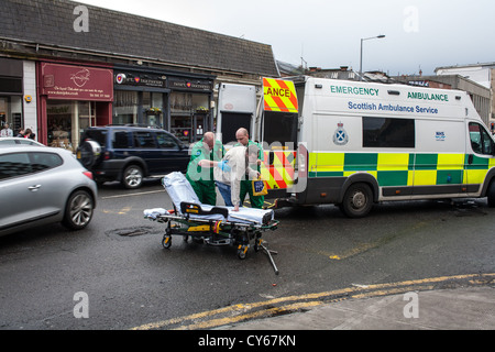 Sanitäter helfen einen verletzten Mann von der Straße. Stockfoto