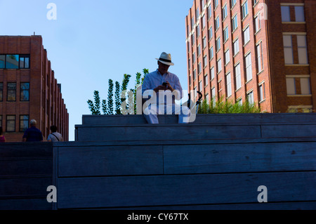 Ein Besucher-Hut für die High Line, Stadtpark, New York tragen eine Panama sitzt auf um seinem Handy zu überprüfen. Stockfoto