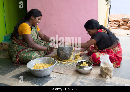 Indische Frauen mischen Jaggery Dal Mischung mit einem Schleifstein dafür Dasara Festival Süßigkeiten in einem indischen Dorf. Indien Stockfoto