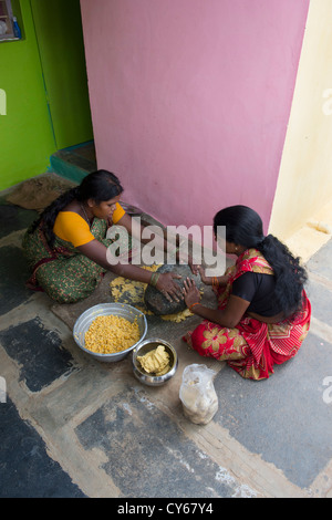 Indische Frauen mischen Jaggery Dal Mischung mit einem Schleifstein dafür Dasara Festival Süßigkeiten in einem indischen Dorf. Indien Stockfoto