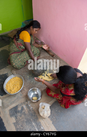 Indische Frauen mischen Jaggery Dal Mischung mit einem Schleifstein dafür Dasara Festival Süßigkeiten in einem indischen Dorf. Indien Stockfoto