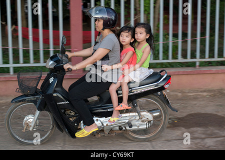 Eine Mutter und ihren beiden Töchtern passieren auf einem Motorrad in Sisophon, Kambodscha Stockfoto