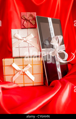 IPad mit Weihnachtsgeschenk auf rotem Grund Stockfoto