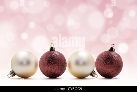 vier Weihnachts-Kugeln in Linie auf rosa Hintergrund mit Lichtern Stockfoto