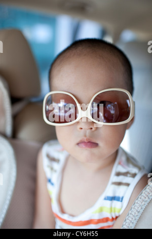 Asiatische junge tragen Sonnenbrille im Auto mit niedlichen Stockfoto