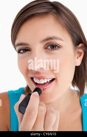 Lächelnde junge Frau Auftragen von Lippenstift auf einem weißen Hintergrund Stockfoto