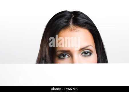 Porträt eines schönen Brünette peeking out hinter leeren weißen Banner. Stockfoto