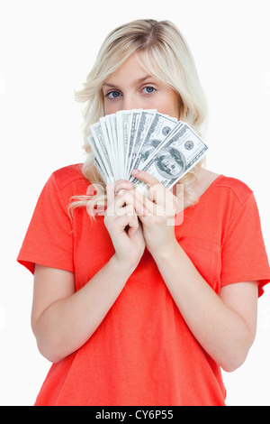 Attraktive Frau verbirgt ihr Gesicht hinter Dollar-Banknoten Stockfoto